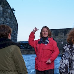 A castle tour guide facing visitors and talking to them