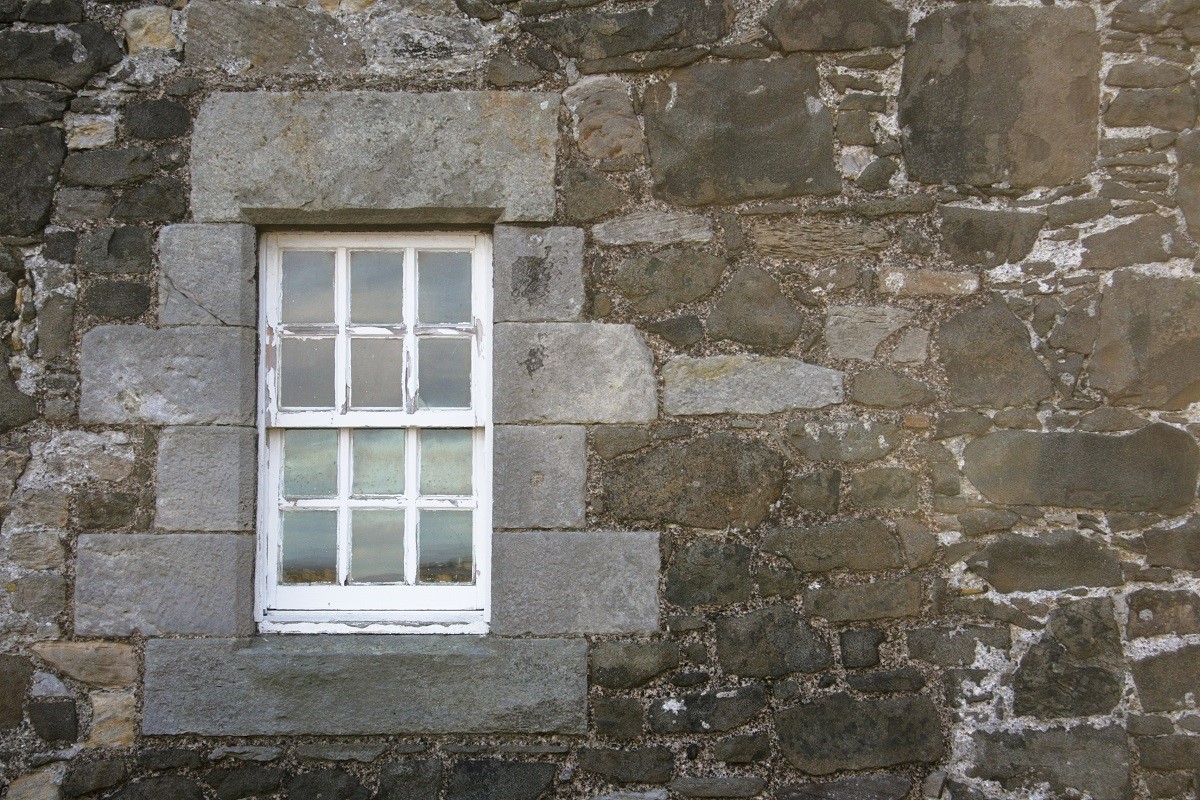 A stone wall with a small sash and case window in a historic building
